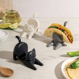 Cat-shaped taco holders on a kitchen counter with food and kitchen items.