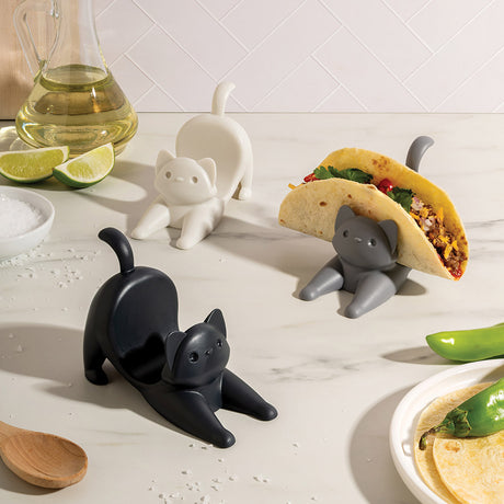 Cat-shaped taco holders on a kitchen counter with food and kitchen items.